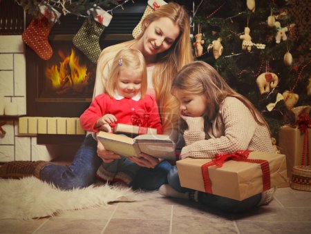 Young mother and her two little daughters with Christmas gifts r