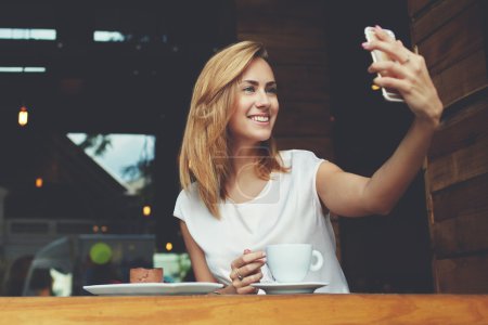 Cheerful woman posing while photographing herself for social network picture, copy space