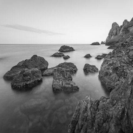Minimalist misty seascape with rocks at long exposure. Black and white
