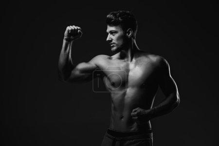 Athletic handsome man showing biceps muscles, studio shot