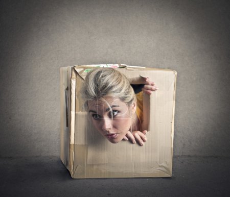 Young blonde girl popping out of a small box