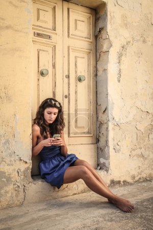 Young woman in blue dress texting on the phone