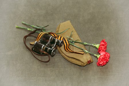 Carnation flowers, George Ribbon and military binoculars. Retro photo to Victory Day on May 9
