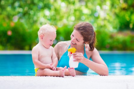 Mother applying sun screen on baby in swimming pool