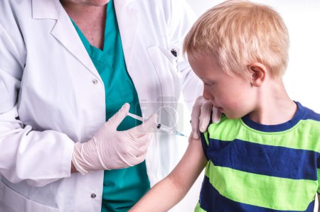 little boy is given an injection by the family doctor