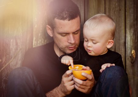 Father with son eating orange