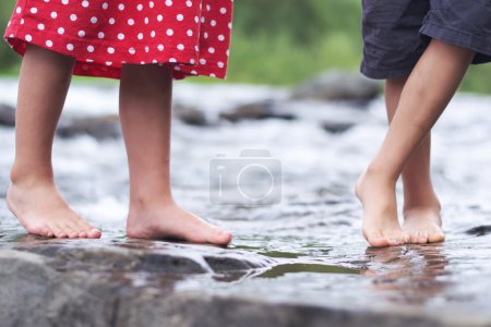 Children soaking feet in a brook