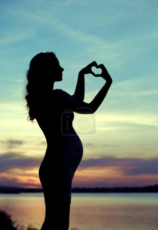 Prgenant woman making the heart sign