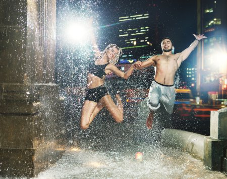 Fit couple jumping in the fountain