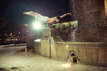 Fit guy doing push-ups in a fountain