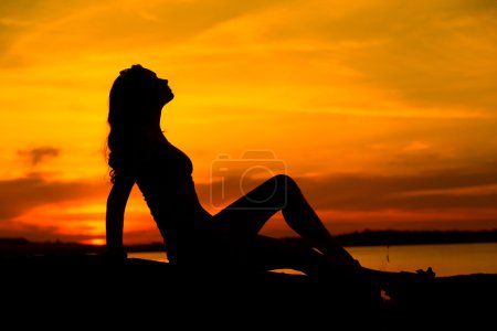 Silhouette of the pregnant woman sitting on the sand