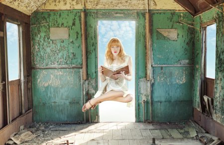 Levitating redhead woman with book