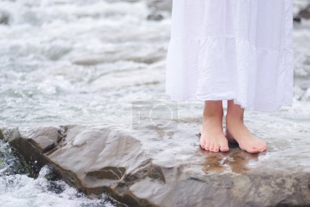 Girl soaking feet in stream