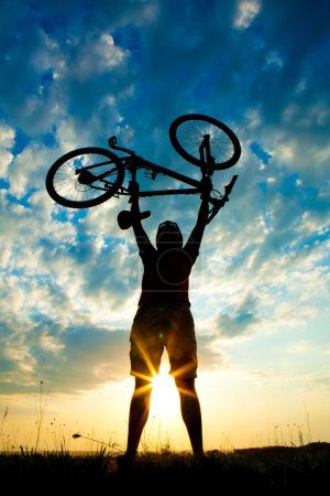 Biker holds bike high up in the sky