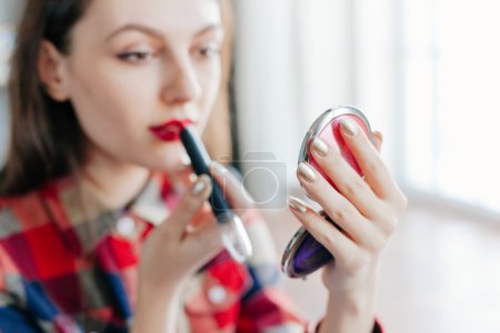 beautiful pin-up girl applying red lipstick