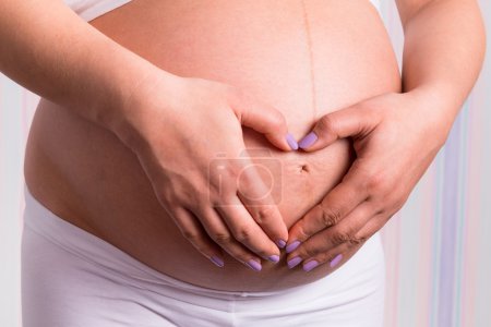 Woman holding hands on pregnant belly