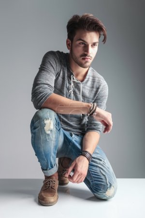  young fashion man relaxing on grey studio background 