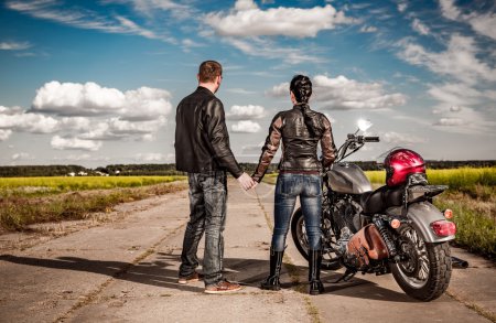 Biker man and girl stands on  road