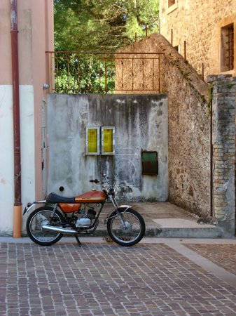 Old italian motorcycle parked in front of stone wall