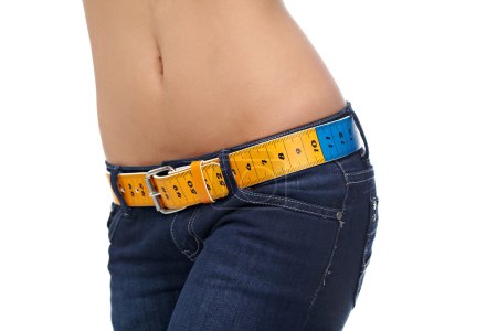 Closeup photo of a slim woman's abdomen and jeans with measuring