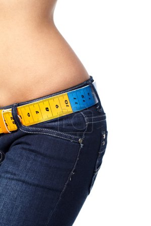 Closeup photo of a slim woman's abdomen and jeans with measuring