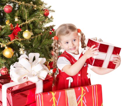 Child giving gift box by christmas tree.