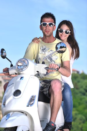 Portrait of happy young love couple on scooter enjoying summer t