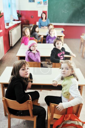 Happy kids with teacher in school classroom