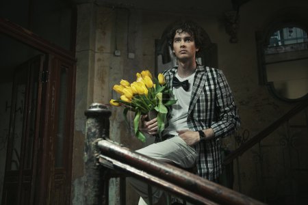 Young fashionable man holding bunch of flowers