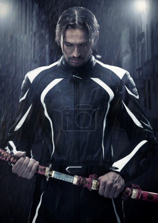 Muscular man holding samurai sword in on a rainy night