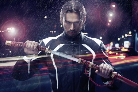 Man holding a samurai sword on a night city street