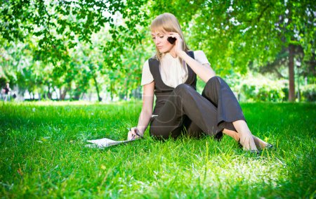 Business woman with phone on grass