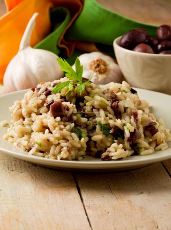 Risotto with black olives on wooden table