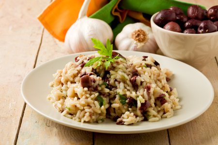 Risotto with black olives on wooden table