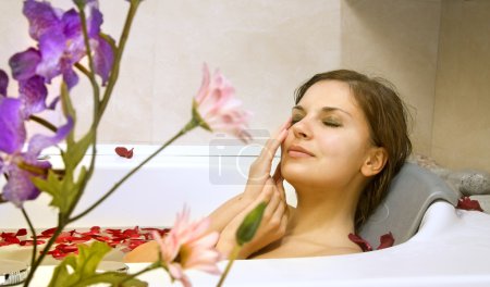 Woman in a bath with rose-petals