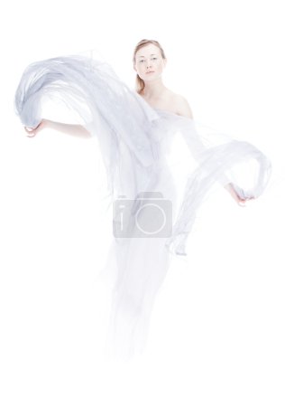 Young woman waving by light fabric