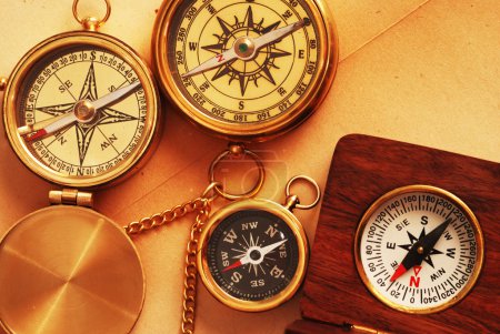 Four antique compasses over old backgrou