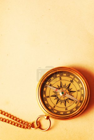 Antique brass compass over old backgroun