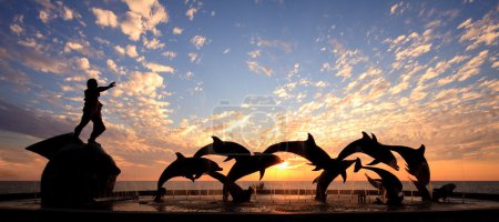 Dolphin statue in front of sunset