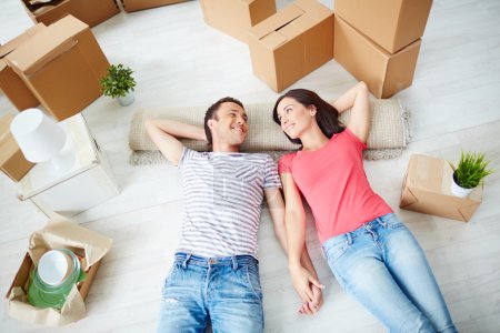 Couple lying on the floor of new house