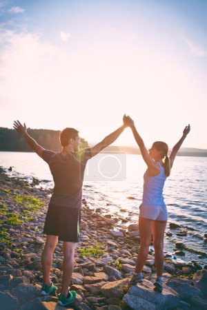Couple on the coastline with raised arms
