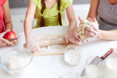 Girl helping mother and sister cook pastry