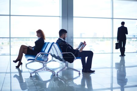 Business partners reading at the airport