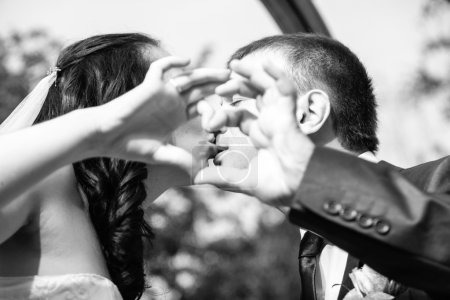 Kissing bride and groom holding hands in shape of heart
