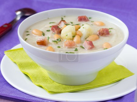 Cream soup with cauliflower, white beans and fried bacon in whit