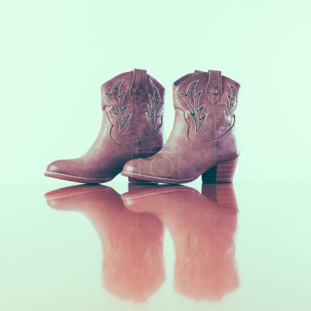 cowboy boots with reflection in wooden floor