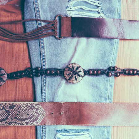 Vintage belts and jeans on wooden background