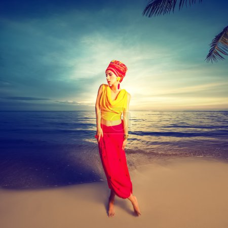 Portrait of a girl in oriental style on the beach at sunset