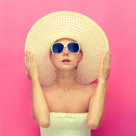 portrait of a girl in a hat on a pink background