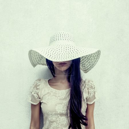 fashion portrait of a sensual girl in a hat against the wall